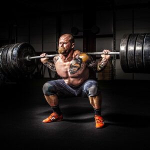 A man lifting weights with a barbell, focused on his exercise.